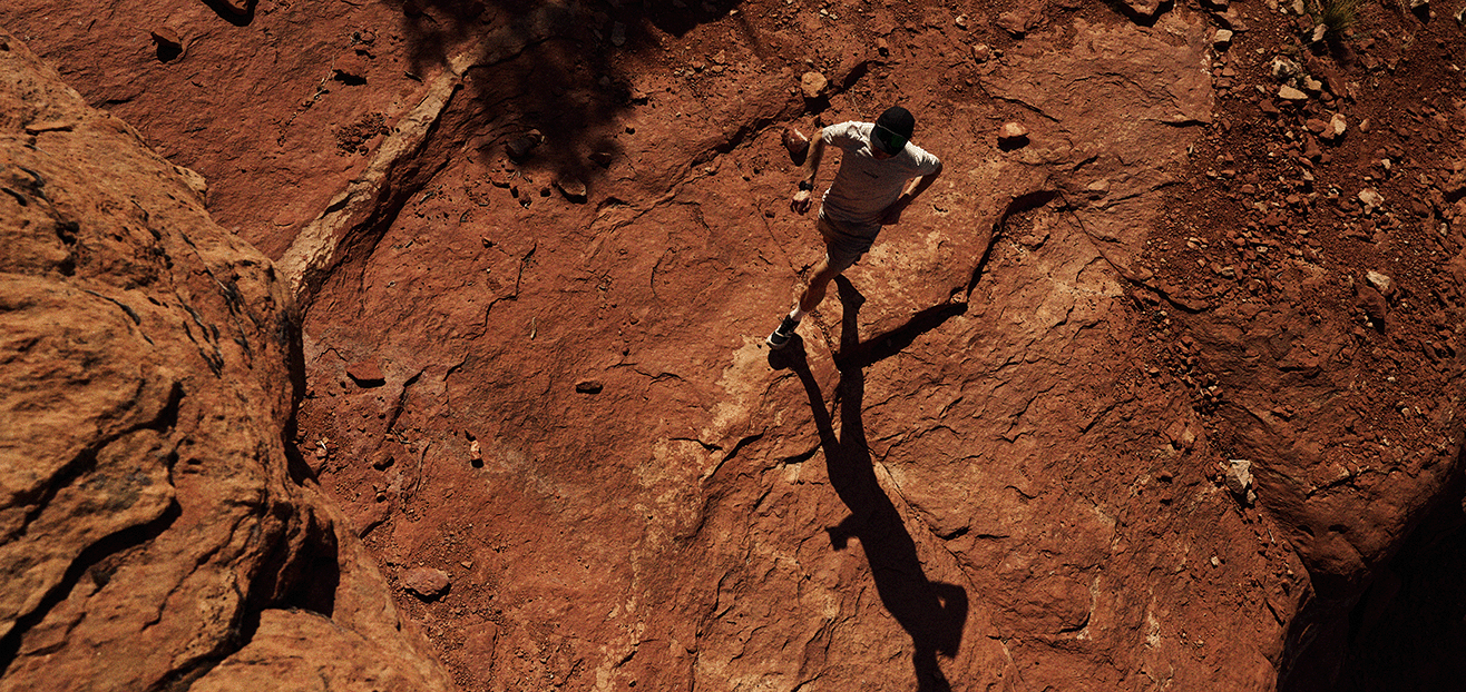Birds eye view of Jack Scott running over red desert rock in Arizona.