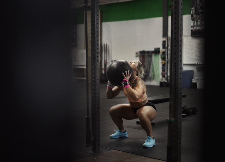 F-LITE MAX trainers, worn by an athlete ready to throw a medicine ball against a wall.