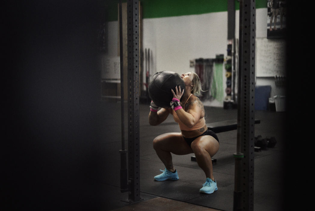 F-LITE MAX trainers, worn by an athlete ready to throw a medicine ball against a wall.