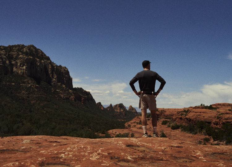 Jack Scott on top of a desert hill, looking out over a red landscape and blue sky.